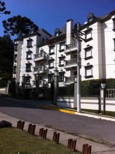 a large white building with balconies on a street at Chateau du Loire Apartamento in Campos do Jordão