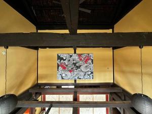 een schilderij aan een muur met een houten tafel bij 藤左ヱ門の宿 in Sudagai
