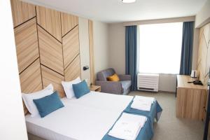 een hotelkamer met een bed en een stoel bij Hotel Forum City in Pazardzhik