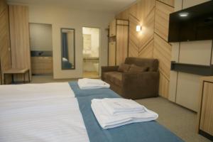 een slaapkamer met een bed, een stoel en een bank bij Hotel Forum City in Pazardzhik