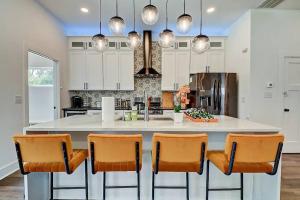 a kitchen with a large white island with orange chairs at NEW Luxury Home 10 Min To Downtown Pool Table in Indianapolis