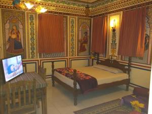 a bedroom with a bed and a tv in it at Hotel Shekhawati Haveli in Mandāwa