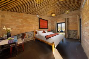 a bedroom with a bed and a table and a desk at Sapaxa Spring Garden Ecolodge in Sapa