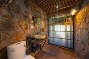 a stone bathroom with a toilet and a sink at Sapaxa Spring Garden Ecolodge in Sa Pa