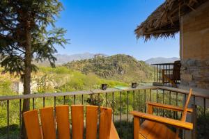 balcón con 2 sillas y vistas a las montañas en Sapaxa Spring Garden Ecolodge en Sa Pa