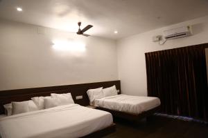 a hotel room with two beds and a ceiling fan at GREEN MOUNT RESORTS in Malaiyāndipattanam