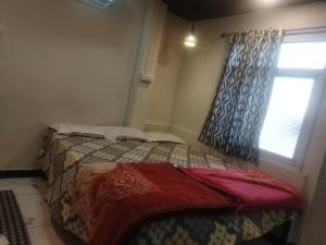 niewielka sypialnia z łóżkiem i oknem w obiekcie New G P Guest house w mieście Ujjain