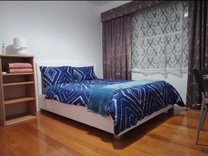 Schlafzimmer mit einem Bett mit blauer Bettwäsche und einem Fenster in der Unterkunft Peaceful cozy home in Kennington
