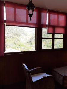 a window with red curtains and a chair in a room at CASA OSO 1 in Pola de Somiedo