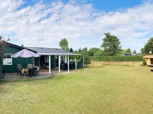 a green house with a table and an umbrella in a yard at Holiday home Middelfart IV in Middelfart
