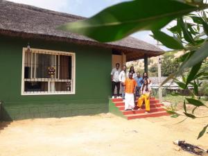 een groep mensen die op de trappen van een groen huis staan bij ATHARV GUEST HOUSE in Hampi