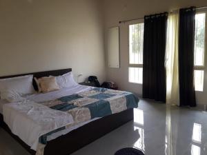 een slaapkamer met een bed en 2 ramen bij ATHARV GUEST HOUSE in Hampi