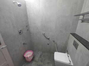 a bathroom with a toilet and a pink bowl at Hotel Pulikeshi - Since 1987 in Bangalore