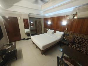 a bedroom with a large white bed and a table at Hotel Pulikeshi - Since 1987 in Bangalore