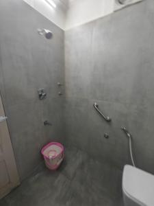 a bathroom with a pink bowl in the corner of a shower at Hotel Pulikeshi - Since 1987 in Bangalore