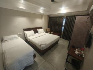 a hotel room with two beds and a television at Hotel Pulikeshi in Bangalore