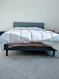 - un lit avec des draps blancs et une tête de lit bleue dans l'établissement Modern, Spacious & Relaxing Home in Sparks, NV, à Sparks