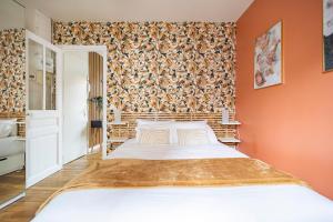 - une chambre avec un grand lit blanc dans une pièce aux murs orange dans l'établissement MM Suites Centre Bacquenois, à Reims