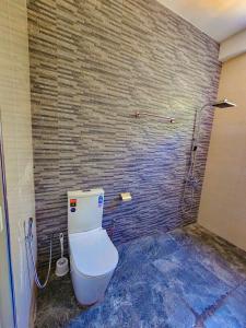 a bathroom with a toilet and a brick wall at Residence Inn in Udawalawe