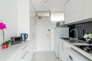 a white kitchen with a sink and a refrigerator at Studio with Stunning Views and Free Parking in Sydney
