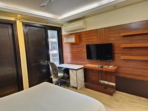 una camera d'albergo con letto e TV di Greenleaf Apartment and Suites, Greater Kailash 1 a Nuova Delhi