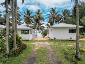 a house with palm trees in front of it at Bella Beach Bungalows in Rarotonga