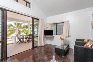 ein Wohnzimmer mit einem Sofa, einem Tisch und einem TV in der Unterkunft Bella Beach Bungalows in Rarotonga