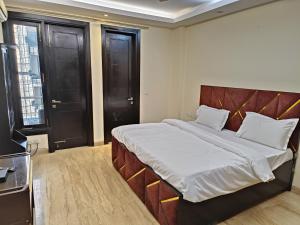 a large bed in a room with black doors at Greenleaf Apartment and Suites, Greater Kailash 1 in New Delhi