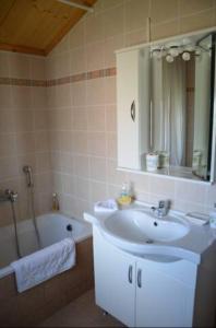 a bathroom with a sink and a tub and a mirror at L'Olivetta in Lithakia