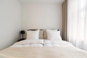 a white bed with white sheets and pillows at Dinesen Collection Luxury Condos in Copenhagen
