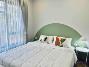 um quarto com uma cama grande e uma janela grande em Borbaimai home em Chiang Rai