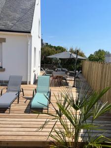 a wooden deck with two chairs and an umbrella at La Maison Des Sables Blancs in Loctudy