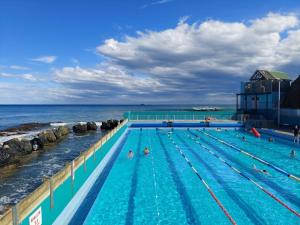 una piscina vicino all'oceano con persone che nuotano di Guest Suite St Clair Beach a Dunedin