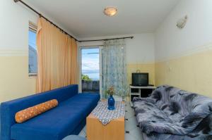 ein Wohnzimmer mit einem blauen Sofa und einem Fenster in der Unterkunft Apartments Sandra in Stomorska