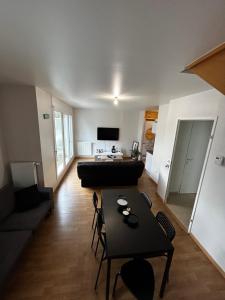 ein Wohnzimmer mit einem Sofa und einem Tisch in der Unterkunft Duplex lumineux tout équipé/RER D/Balcon/Parking in Corbeil-Essonnes