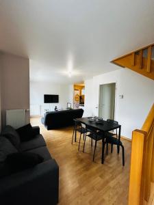 ein Wohnzimmer mit einem schwarzen Sofa und einem Tisch in der Unterkunft Duplex lumineux tout équipé/RER D/Balcon/Parking in Corbeil-Essonnes