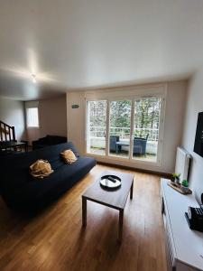 ein Wohnzimmer mit einem blauen Sofa und einem Tisch in der Unterkunft Duplex lumineux tout équipé/RER D/Balcon/Parking in Corbeil-Essonnes