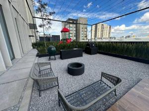a patio with two chairs and a table and a grill at Lujoso Departamento en Angelópolis, Puebla. in El Gallinero