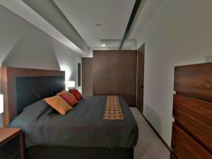 1 dormitorio con 1 cama con 2 almohadas de color naranja en Lujoso Departamento en Angelópolis, Puebla., en El Gallinero