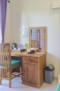 escritorio de madera con silla y teléfono en Ped Cottage en Nusa Penida
