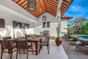 uma sala de jantar com mesa e cadeiras e uma piscina em Echo Beach Villa and Apartment em Canggu