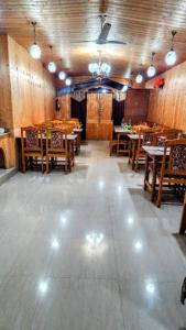 斯利那加的住宿－Nigeen Residency Resort , Srinagar，用餐室配有桌子和木桌及椅子