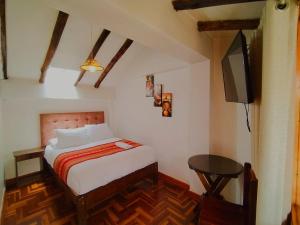 a bedroom with a bed and a flat screen tv at Hostal Paqarina San Blas in Cusco