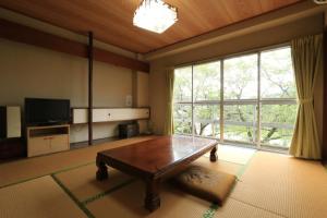een woonkamer met een tafel en een groot raam bij ニュー筑水荘 in Ukiha