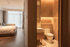 a bedroom with a bed and a toilet and a sink at Guus Hotel in Zengcheng