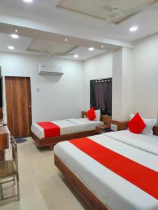 - 2 lits dans une chambre avec des draps rouges et blancs dans l'établissement Hotel Nawanagar Residency, à Jamnagar