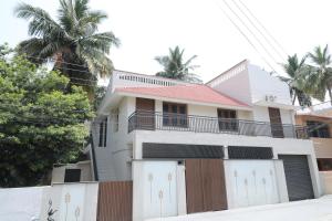 a house with a fence and palm trees at Vellore Service Apartments Unit 1 in Vellore