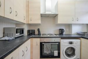 a kitchen with white cabinets and a washer and dryer at APlaceToStay Central London Apartment, Zone 1 OX in London