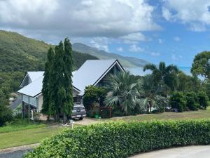 a house with a silver roof and palm trees at The Cowrie Shell, Hydeaway Bay in Hideaway Bay
