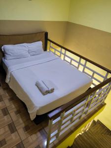 uma cama com lençóis brancos e almofadas em PROMOSIA GUEST HOUSE em Surabaya